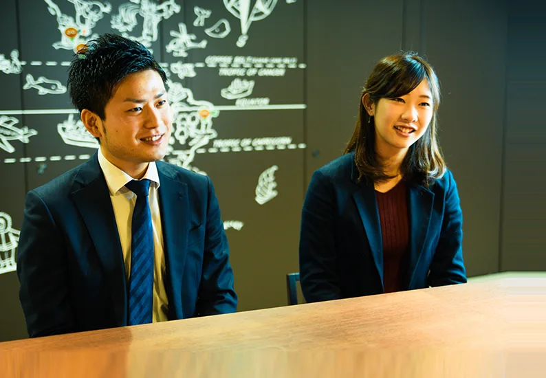 壁画のある部屋で対談する世話役の社員と新入社員