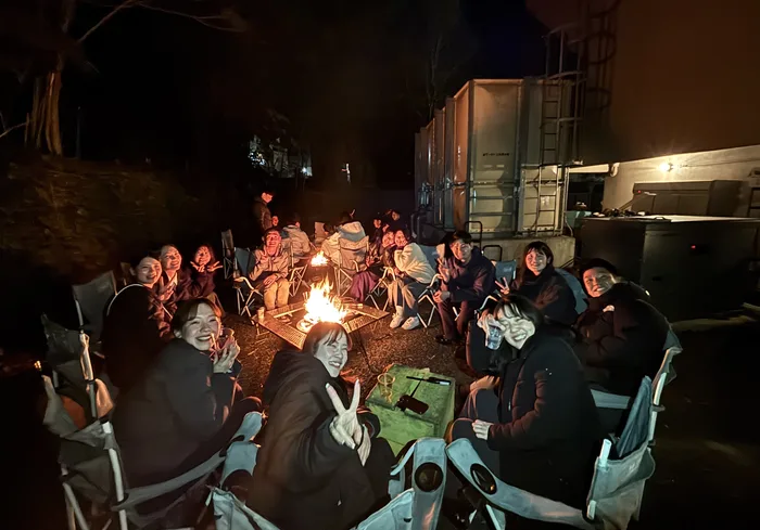 夜の会場で焚き火を囲む参加者たち