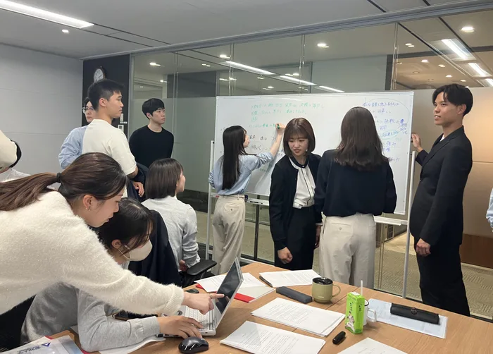 発表資料を囲んで話し合う新入社員たち
